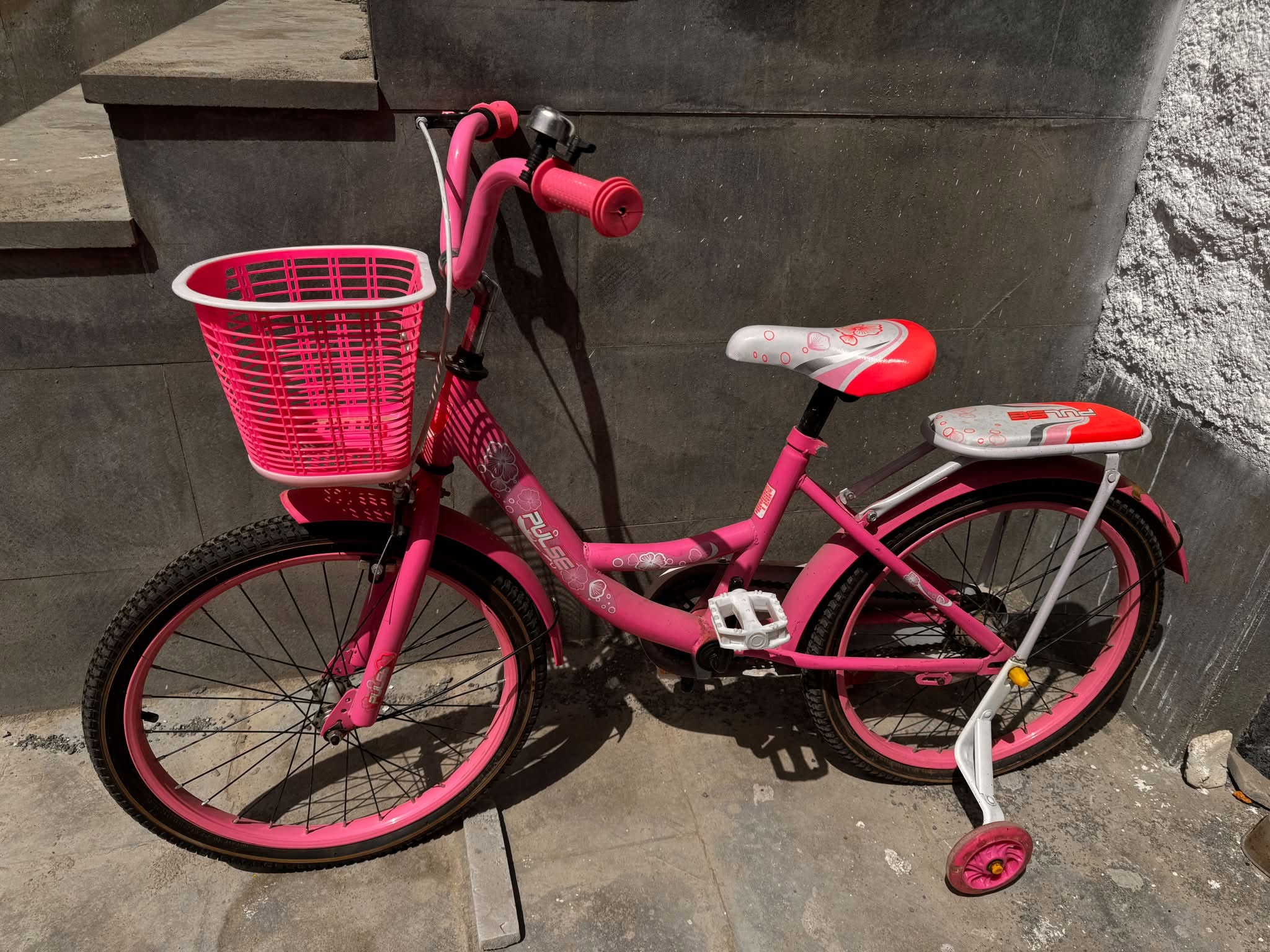 Pink children's bicycle with training wheels